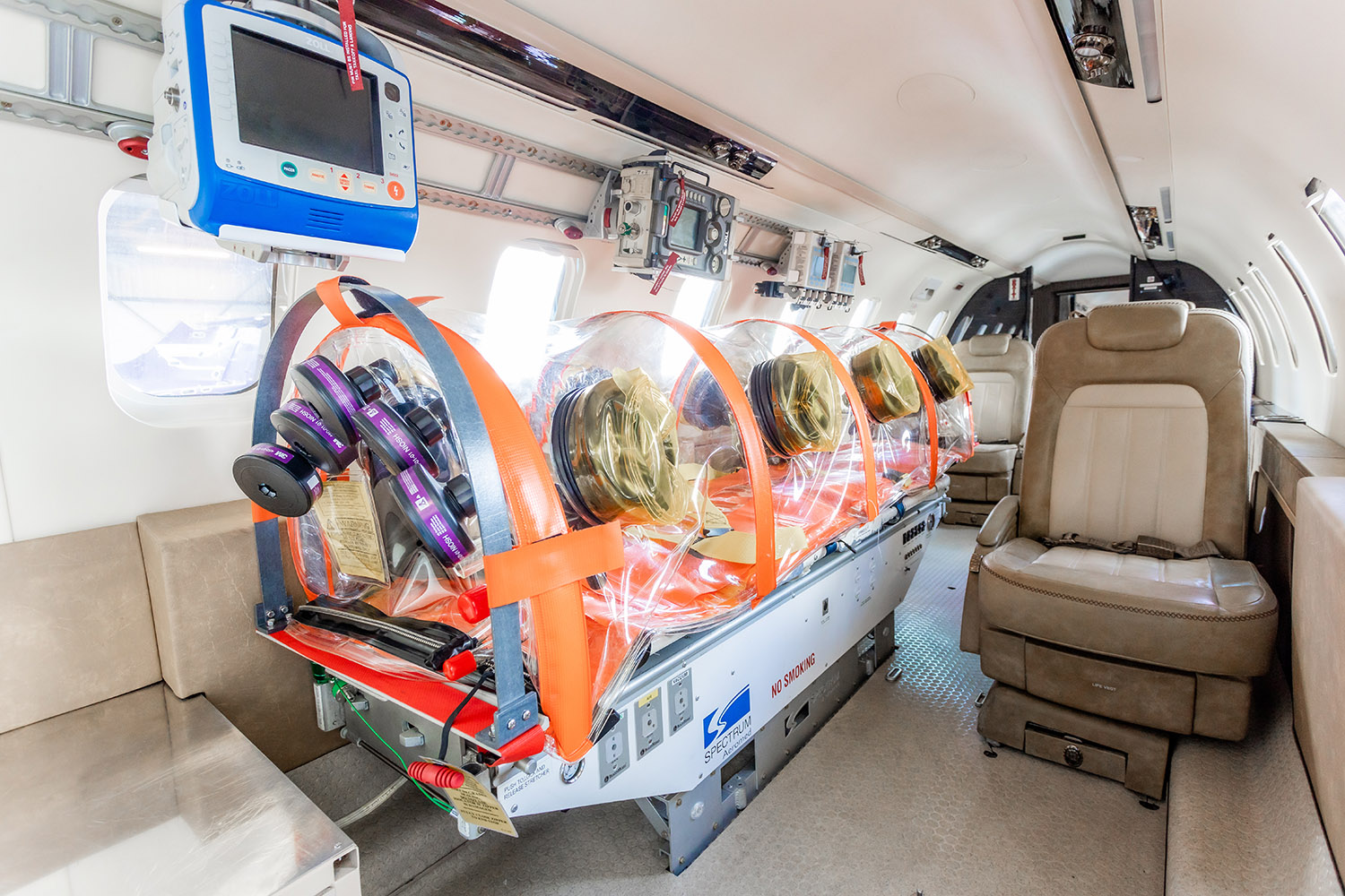 the inside of an airplane with a stretcher and a monitor hanging from the ceiling