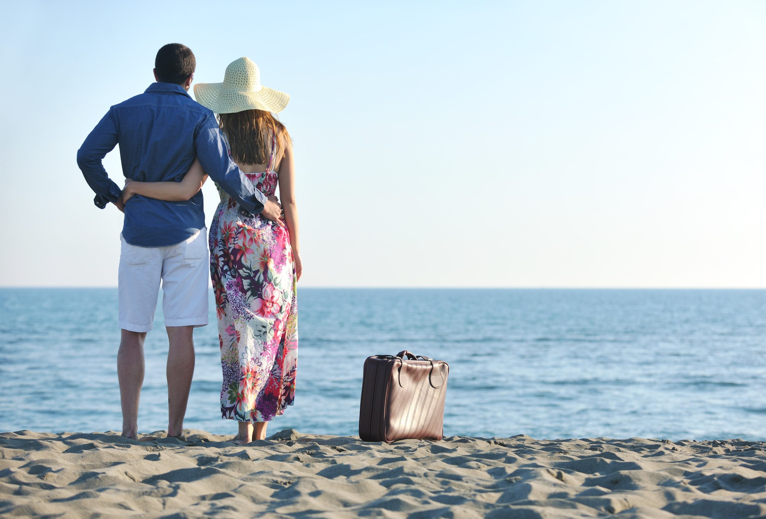 couple-on-beach-with-travel-bag